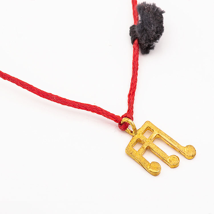 Necklace with a red cord and a K18 gold musical note motif.