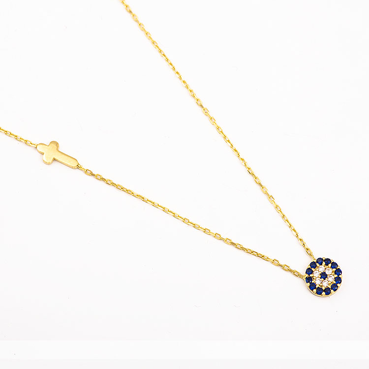 K14 gold necklace with a cross and a round evil eye adorned with blue stones.